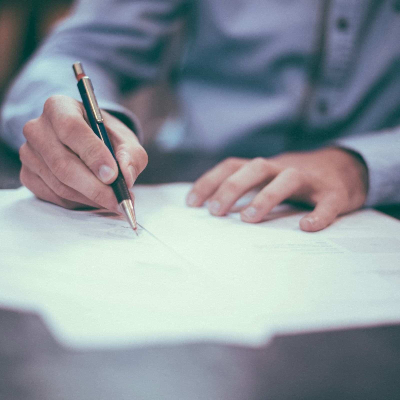 Una mano firmando un documento con un bolígrafo