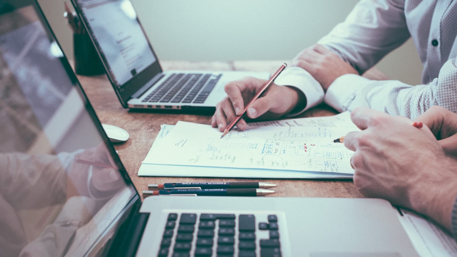 Business owner reviewing customer data and a plan on a laptop