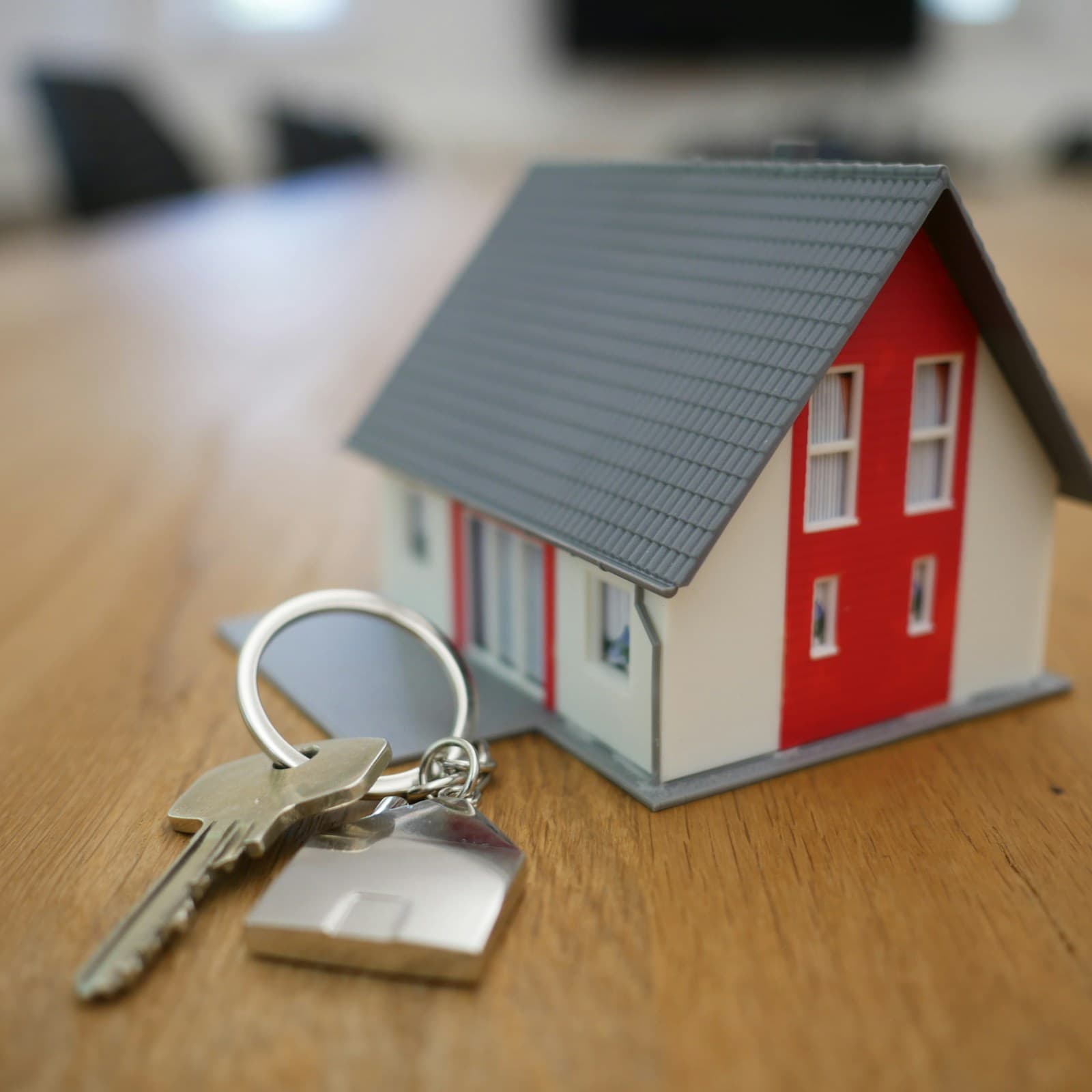 Una casa en miniatura y una llave sobre una mesa de madera